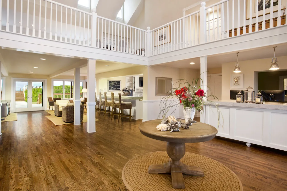 An open-concept lounge and dining space with a central round table adorned with decorative elements. High ceilings and expansive windows flood the room with natural light, creating a comfortable and inviting environment.
