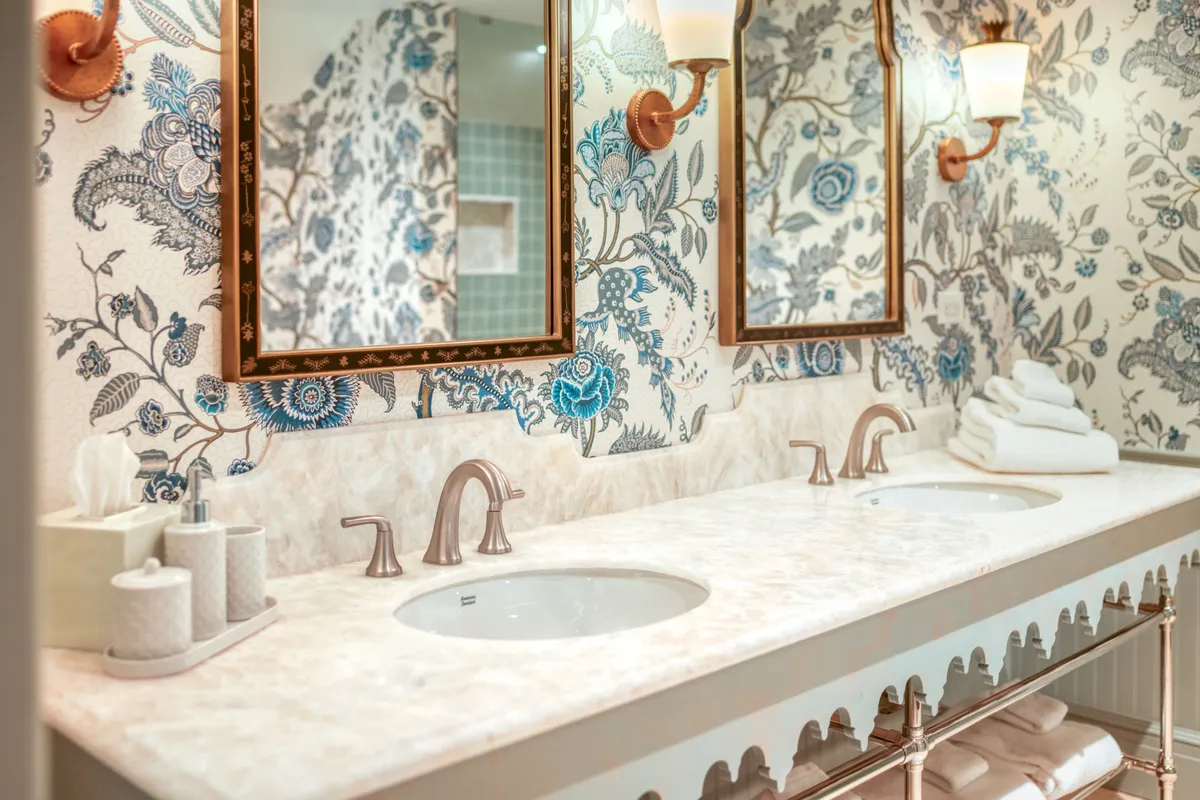 The image showcases a bathroom with double vanity sinks, ornate mirrors, and floral wallpaper. The refined atmosphere encourages self-care routines, with an emphasis on refreshing morning rituals or winding down in the evening.